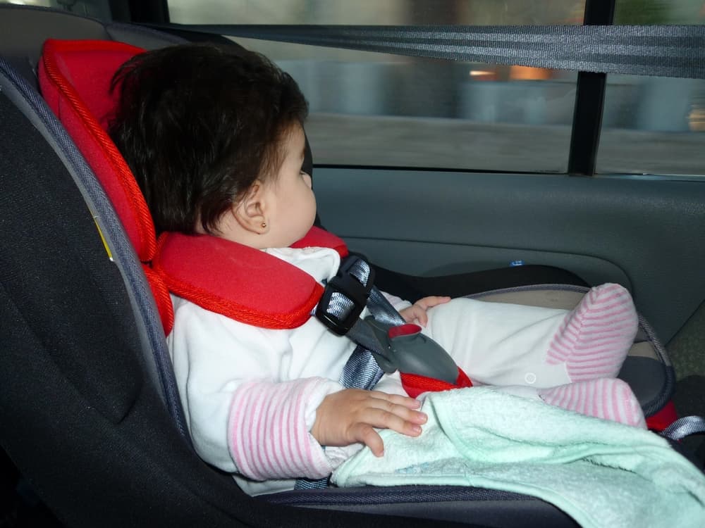 Baby traveling by car in his safety seat. Little girl in her car seat. Baby safety belt. Safe journey. Caution. Booster. car interior Window. Protection. Traffic rules.