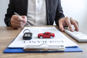 Car rental and insurance concept: A young salesman receives money and hands over the car keys to a customer after they sign an agreement contract with approval.