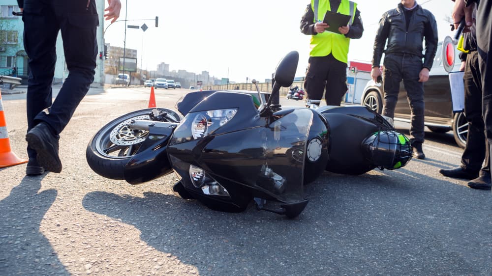 A broken motorcycle at the scene of a road accident.