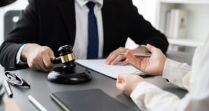 A lawyer is sitting at a law firm office desk, reviewing and drafting legal documents with a paperwork.