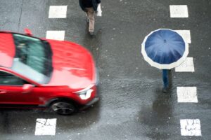 Pedestrians in a dangerous crosswalk situation as vehicles speed through a city street. 