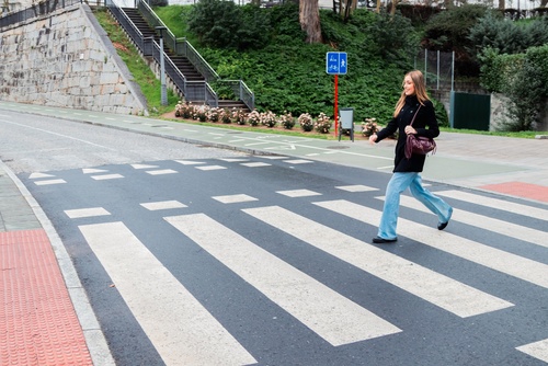 Young woman crossing pedestrian crosswalk on city street