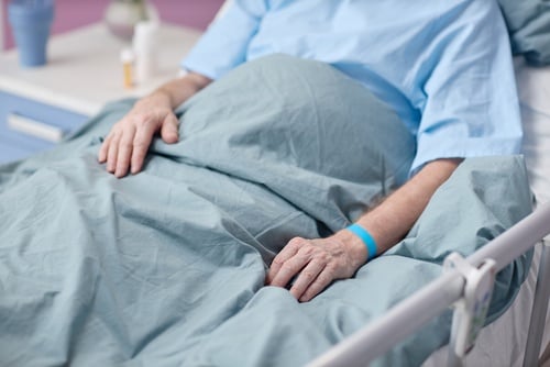 elderly patient lying in hospital bed wearing identification wristband