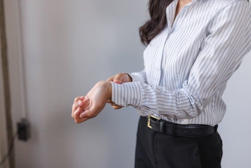 woman in business attire clutching wrist indicating arm or wrist pain