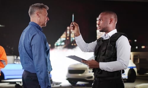 officer in tactical vest holding pen administering roadside DUI field sobriety test